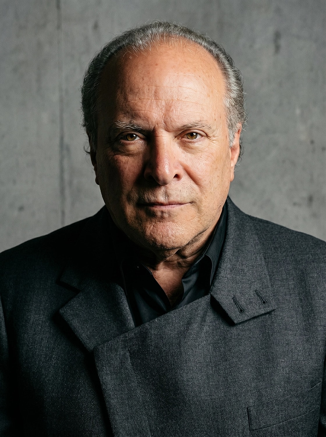 Man in dark suit against textured background.