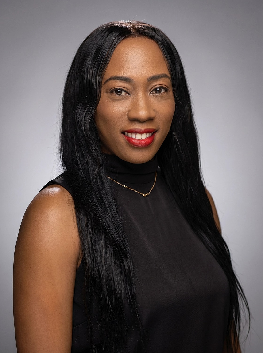 Smiling woman with long black hair and necklace.