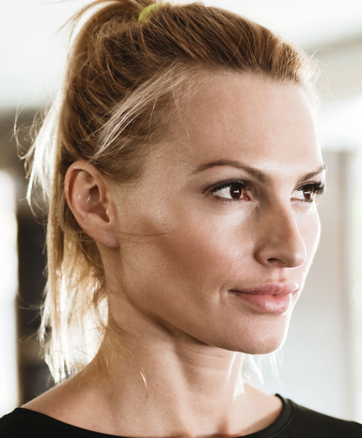 Close-up of an Avon facial fat transfer model with ponytail and natural makeup.