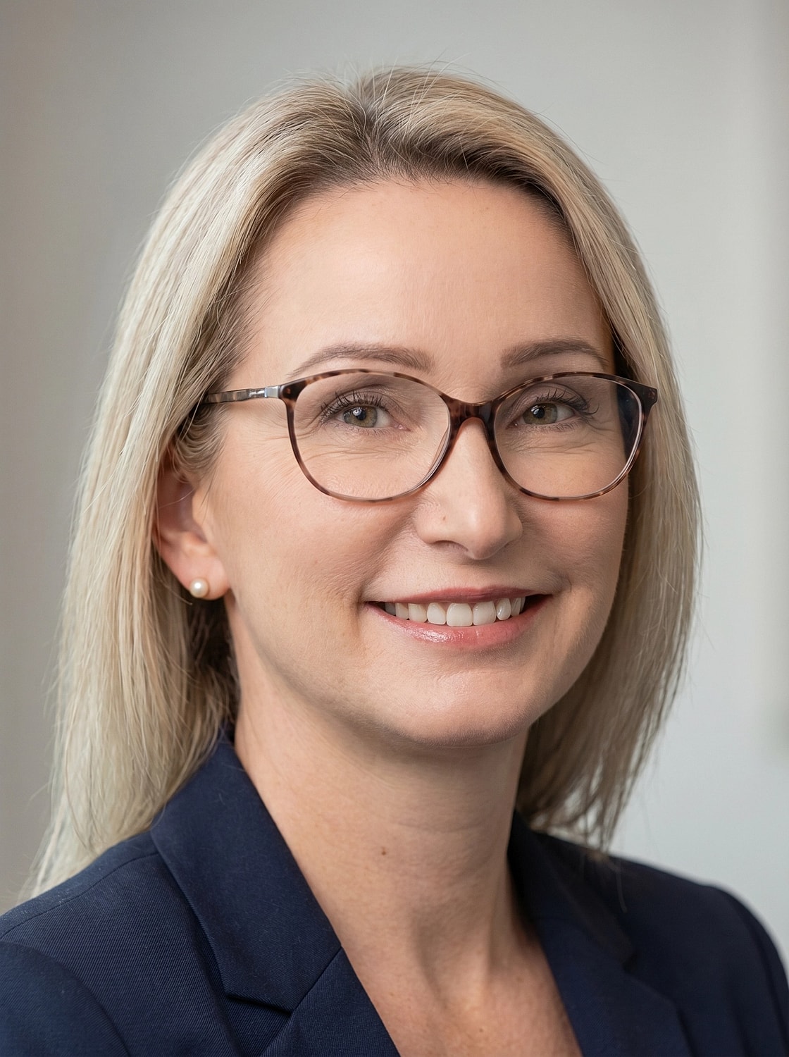 Smiling woman with glasses in professional attire.