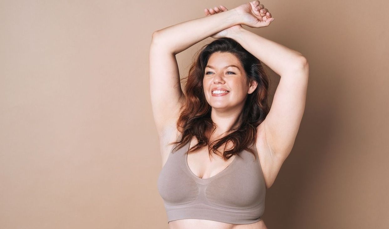 Smiling woman in lingerie, natural light setting.