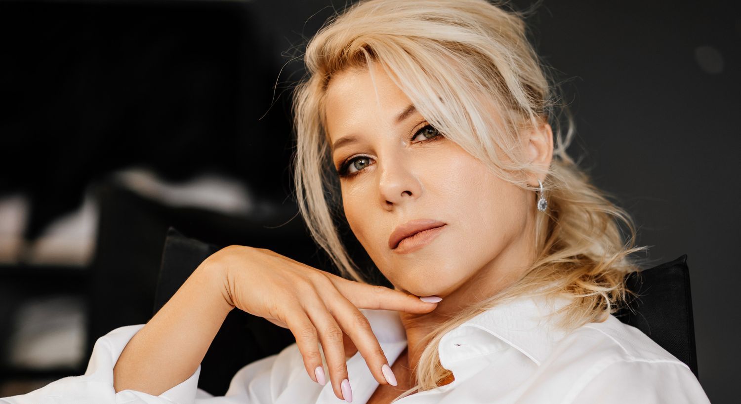 Woman in a white shirt posing thoughtfully.