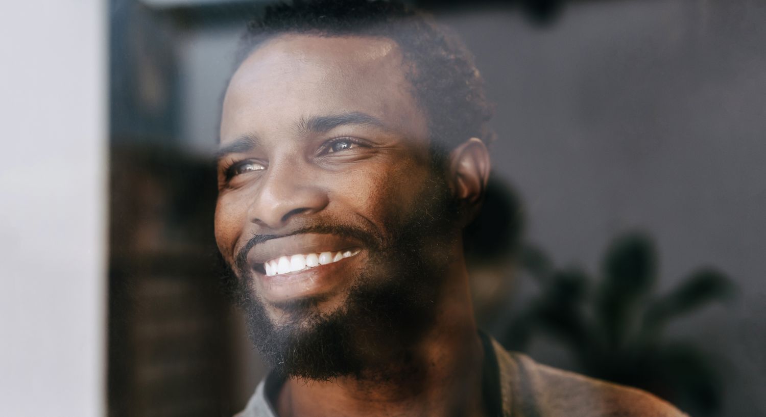 Smiling man looking out of a window.