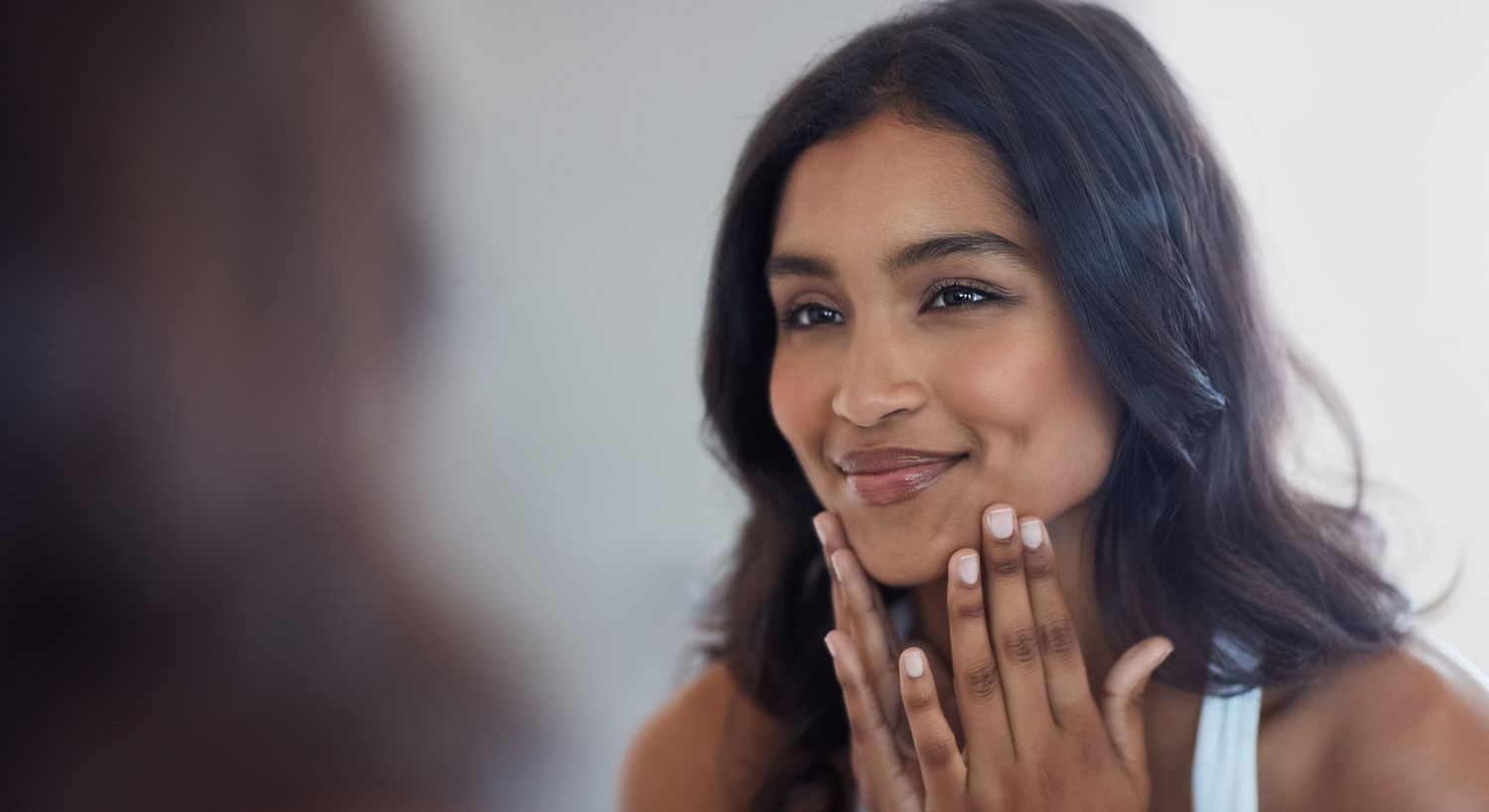 Smiling woman with long hair and hand on forehead.